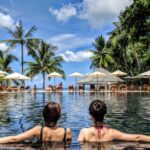 two woman leaning on inground pool tile